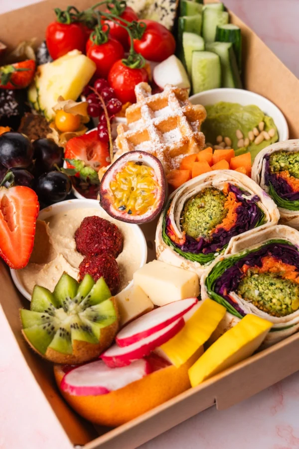 Vegetarische Brunch Box aus Wien mit frischem Obst, Hummus, Falafel-Wraps, Avocado, Waffel, Käse und Gemüsesticks – ideal für gesunden Brunch oder Catering.