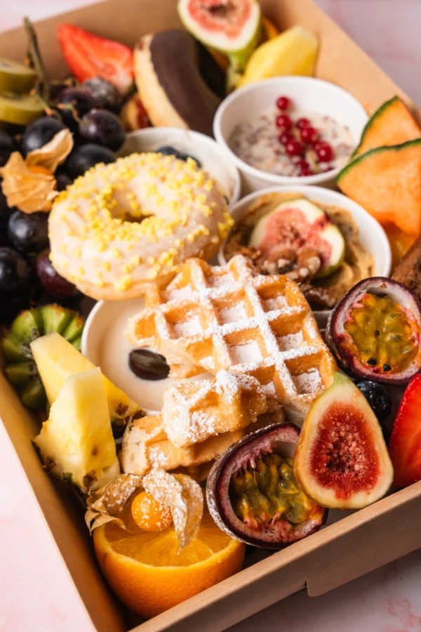 Vegetarische süße Brunch Box aus Wien mit Donuts, Waffeln, Müsli, frischem Obst, Nüssen und Aufstrichen – perfekt für Frühstück, Brunch oder Geschenkideen.